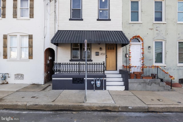 townhome / multi-family property with covered porch and brick siding