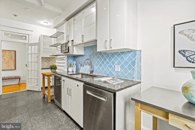 kitchen featuring white cabinets, a sink, granite finish floor, and stainless steel dishwasher