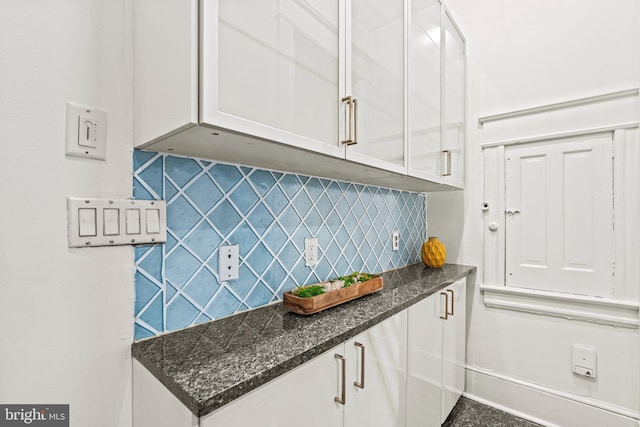 kitchen with baseboards, white cabinets, backsplash, and dark stone countertops