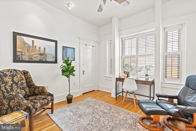 living area with ceiling fan, baseboards, and wood finished floors