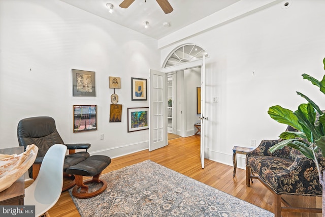 sitting room with wood-type flooring, ceiling fan, and baseboards