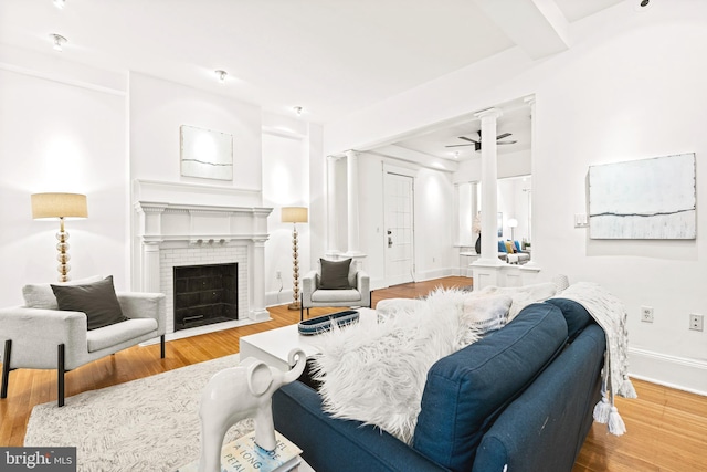 living area featuring a ceiling fan, a fireplace, baseboards, and wood finished floors