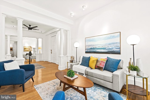 living room with baseboards, light wood-style flooring, a ceiling fan, and ornate columns