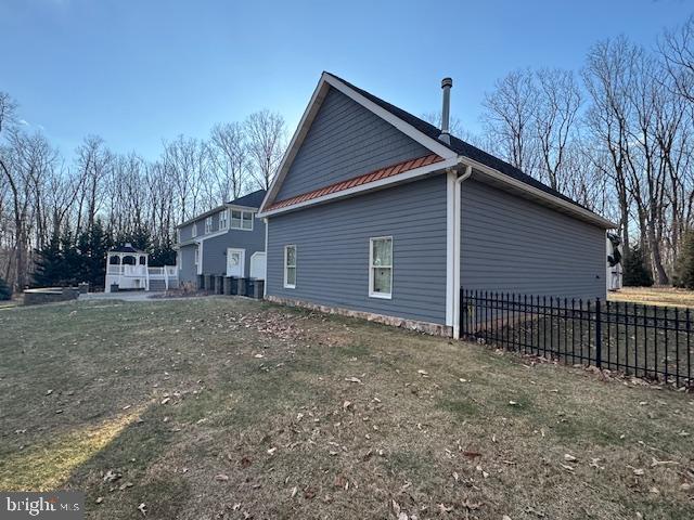 view of side of property with metal roof and fence