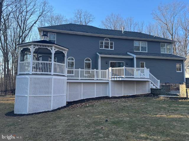 rear view of house featuring a lawn, a deck, and a gazebo