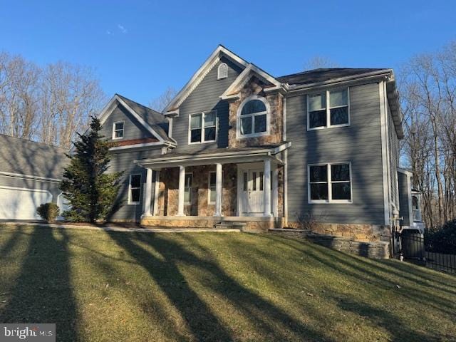 view of front facade featuring a porch, stone siding, and a front lawn