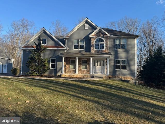 view of front of property with stone siding, a front lawn, and a porch