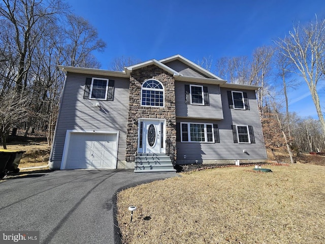 traditional-style house with a garage, stone siding, and aphalt driveway