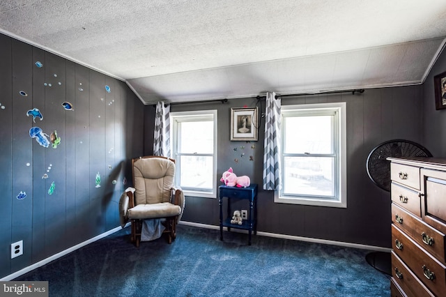 living area featuring lofted ceiling, baseboards, dark carpet, and a textured ceiling