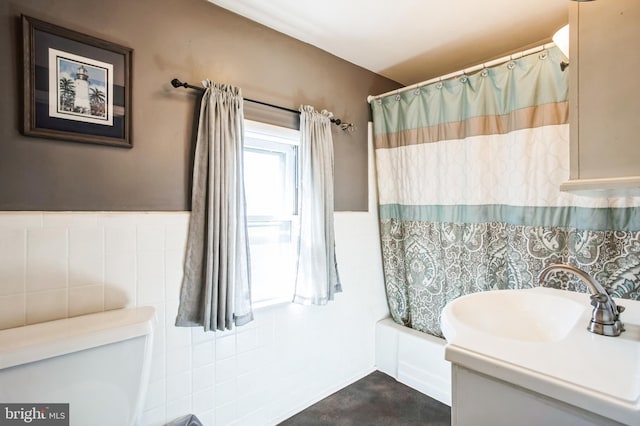 full bath with shower / bathtub combination with curtain, wainscoting, a sink, and tile walls