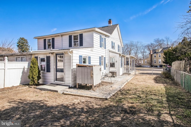 rear view of property featuring a fenced backyard and a chimney