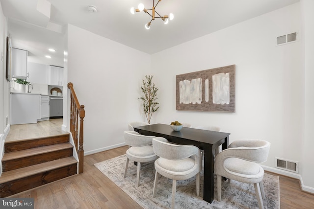 dining room featuring light wood-style floors, baseboards, a chandelier, and visible vents