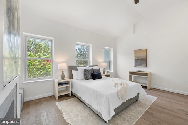 bedroom featuring baseboards, vaulted ceiling, and wood finished floors