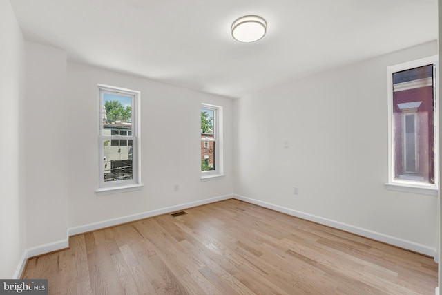 unfurnished room with visible vents, light wood finished floors, and baseboards