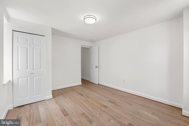 unfurnished bedroom with baseboards, wood finished floors, and a closet