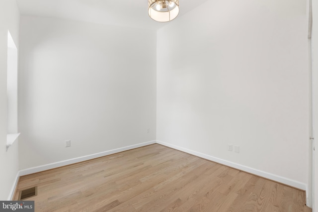 empty room featuring baseboards, wood finished floors, and visible vents