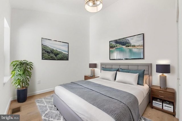 bedroom with baseboards, visible vents, and wood finished floors