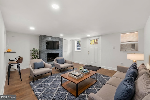 living area with wood finished floors, a fireplace, baseboards, recessed lighting, and cooling unit