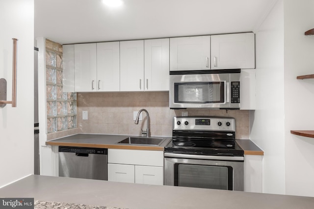 kitchen with a sink, appliances with stainless steel finishes, tasteful backsplash, and white cabinetry