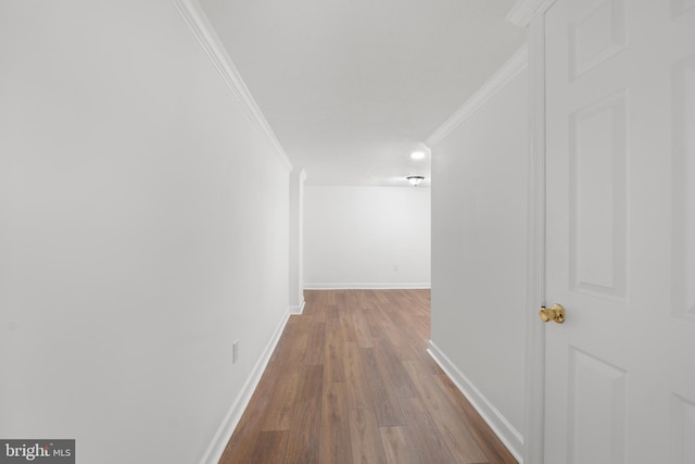 corridor with crown molding, baseboards, and wood finished floors