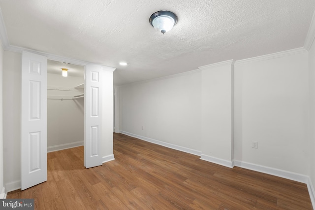 below grade area with baseboards, ornamental molding, a textured ceiling, and wood finished floors