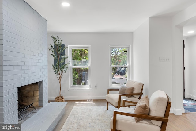 living area with baseboards, recessed lighting, light wood finished floors, and a brick fireplace