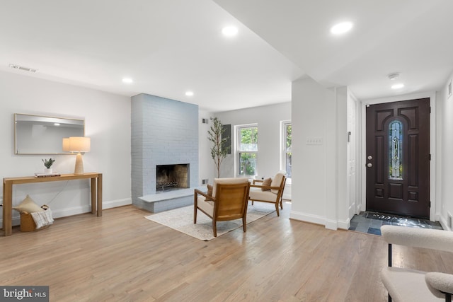 foyer entrance featuring visible vents, a fireplace, baseboards, recessed lighting, and light wood-type flooring