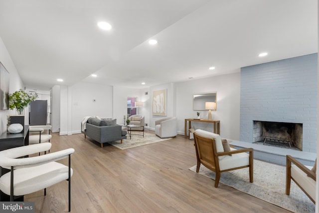 living area with light wood-type flooring, recessed lighting, baseboards, and a brick fireplace