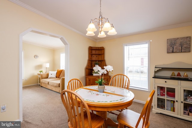 carpeted dining room featuring a chandelier, arched walkways, crown molding, and baseboards