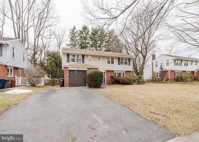 view of front of house with driveway, a front yard, fence, and brick siding