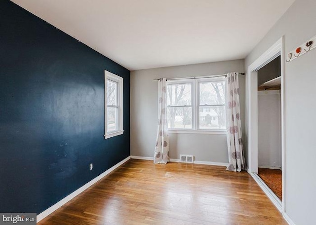 unfurnished bedroom featuring visible vents, baseboards, and wood finished floors