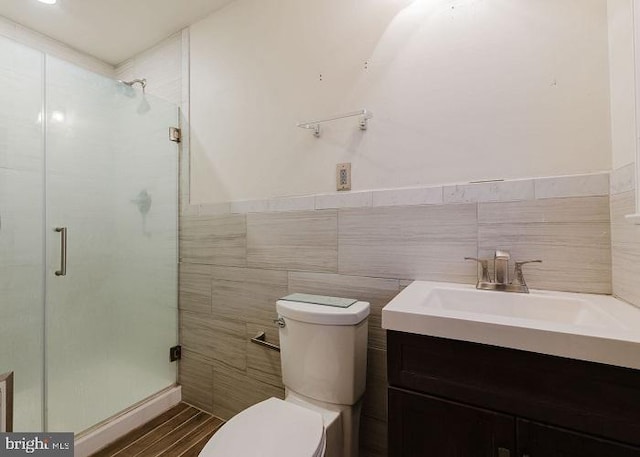 full bath featuring a stall shower, tile walls, toilet, and vanity