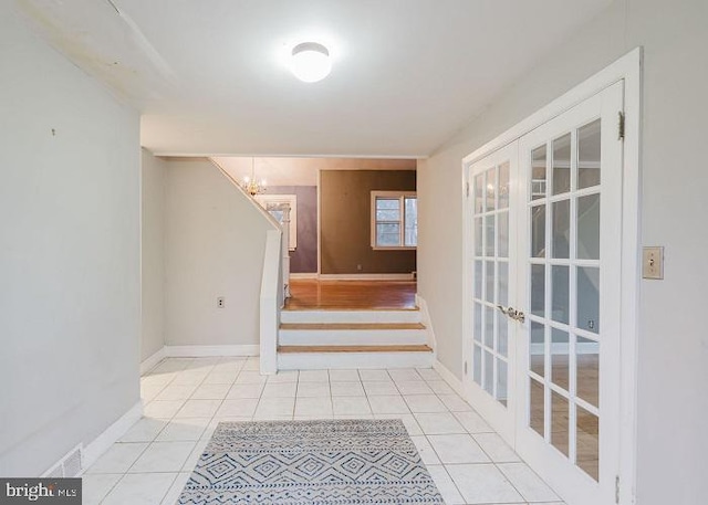 stairway featuring tile patterned flooring, baseboards, a notable chandelier, and french doors