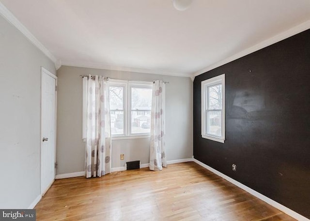 spare room with crown molding, light wood-style flooring, and baseboards