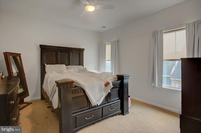 bedroom featuring baseboards, ceiling fan, multiple windows, and light colored carpet