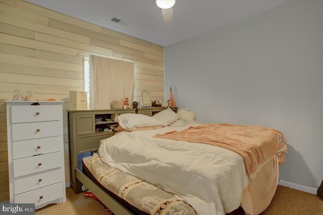 bedroom featuring carpet floors, wood walls, visible vents, and baseboards