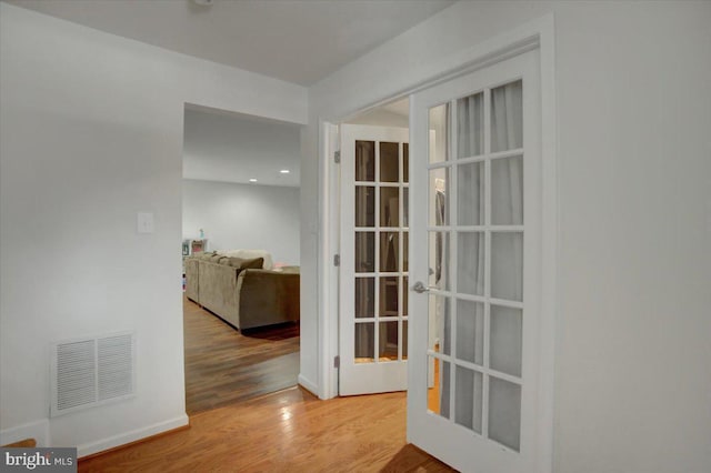 hallway featuring visible vents and wood finished floors