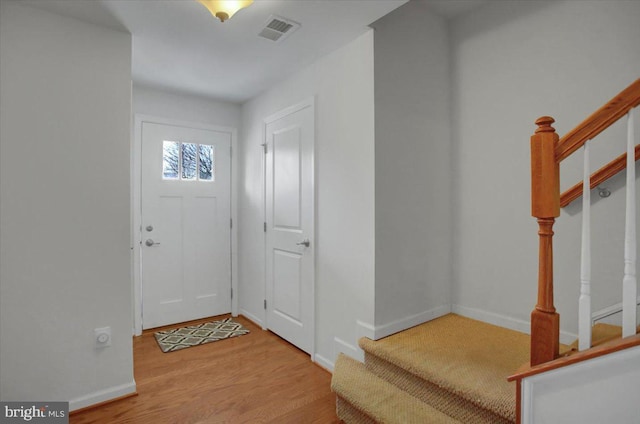 foyer with visible vents, stairway, baseboards, and wood finished floors