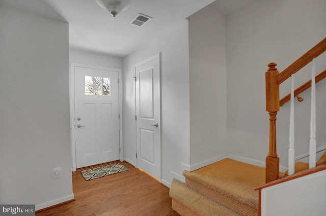 foyer featuring stairway, wood finished floors, visible vents, and baseboards