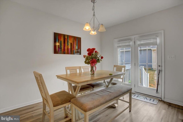 dining area with light wood-style floors, baseboards, and an inviting chandelier