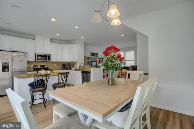 dining area with light wood-style flooring, baseboards, and recessed lighting