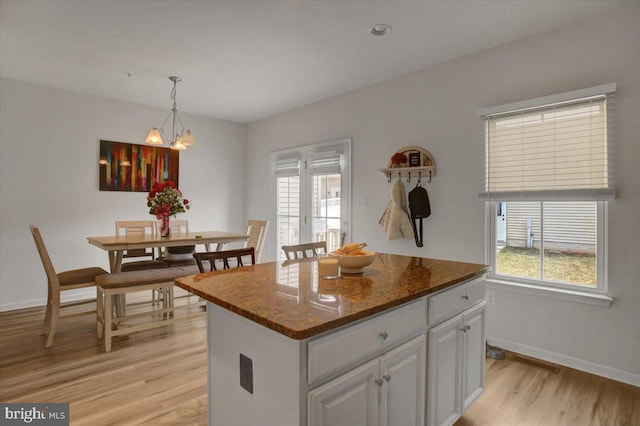 kitchen with light wood-style flooring, white cabinetry, a wealth of natural light, and decorative light fixtures