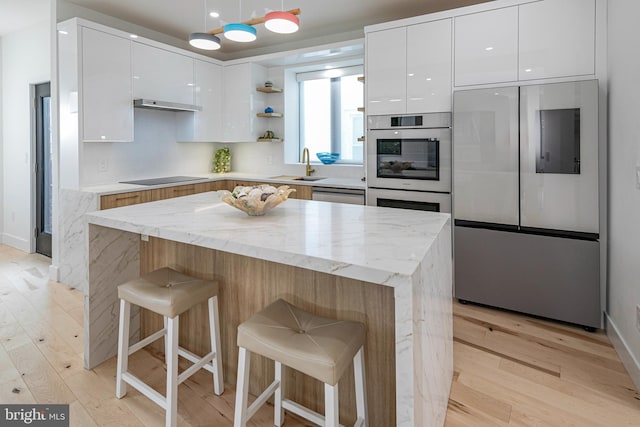 kitchen featuring a breakfast bar, modern cabinets, appliances with stainless steel finishes, and white cabinets