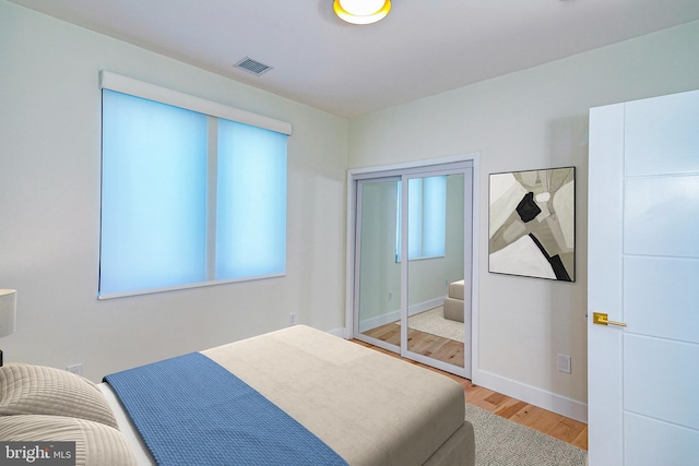 bedroom featuring baseboards, visible vents, and wood finished floors