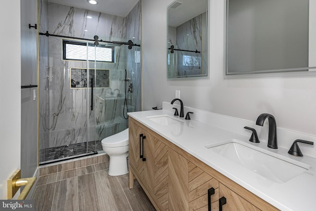 full bath with a marble finish shower, a sink, toilet, and double vanity