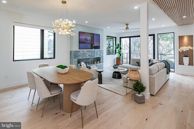 dining room featuring baseboards, light wood-type flooring, a tile fireplace, and recessed lighting