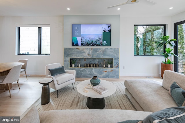 living area featuring recessed lighting, a fireplace, baseboards, and wood finished floors