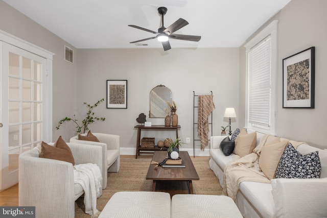 living area with visible vents, baseboards, light wood-style floors, and ceiling fan