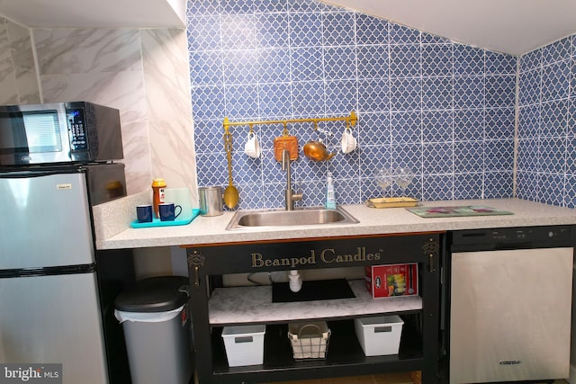 kitchen with tile walls, light countertops, backsplash, appliances with stainless steel finishes, and a sink