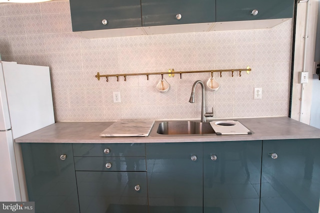 kitchen featuring blue cabinets, freestanding refrigerator, light countertops, and a sink